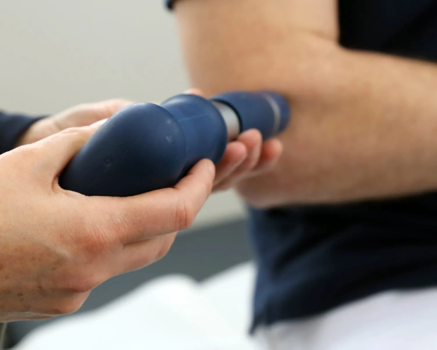 Stoßwellen-Handstück des Gymna ShockMaster in der Anwendung am Fuß eines Patienten